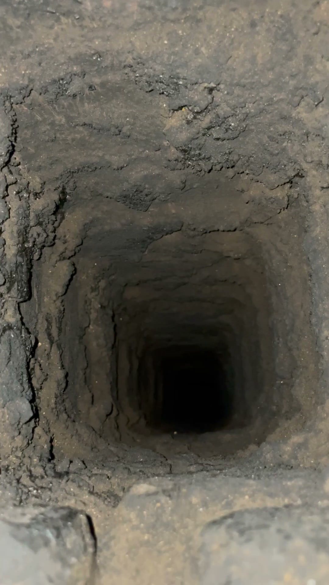 Pohled do zděného komína, mezi cihelnými řadami jsou vydrolené spáry