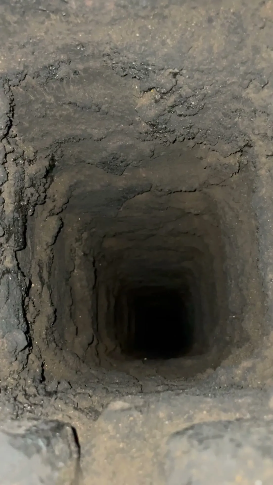 Pohled do zděného komína, mezi cihelnými řadami jsou vydrolené spáry